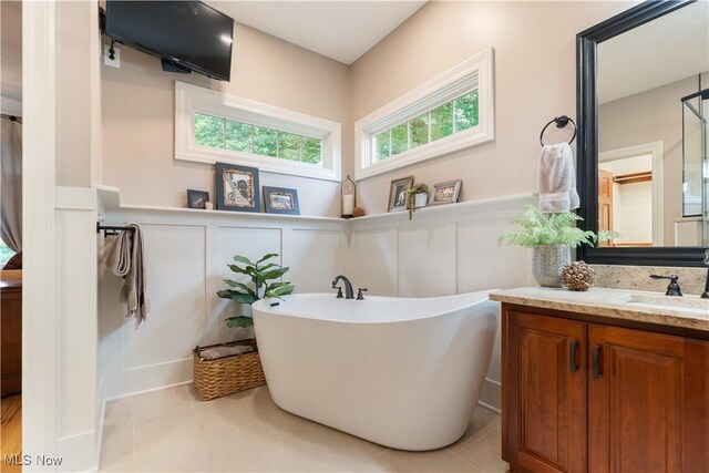 1588 Eagle Watch St NE, Canton, OH 44721 - bathroom featuring a freestanding tub, vanity, a decorative wall, tile patterned floors, and a wainscoted wall