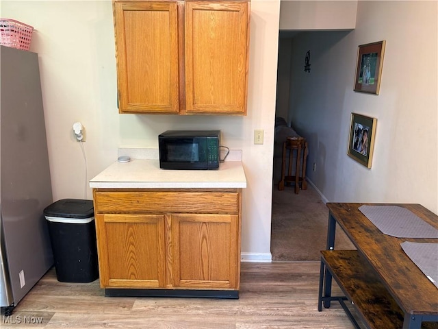 732 E High St, Alliance, OH 44601 - kitchen with black microwave, light wood-style flooring, light countertops, and freestanding refrigerator