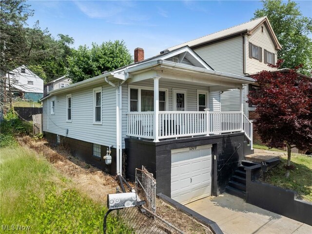 1309 7th St N, Martins Ferry, OH 43935 - view of front facade featuring a chimney, covered porch, a garage, and concrete driveway
