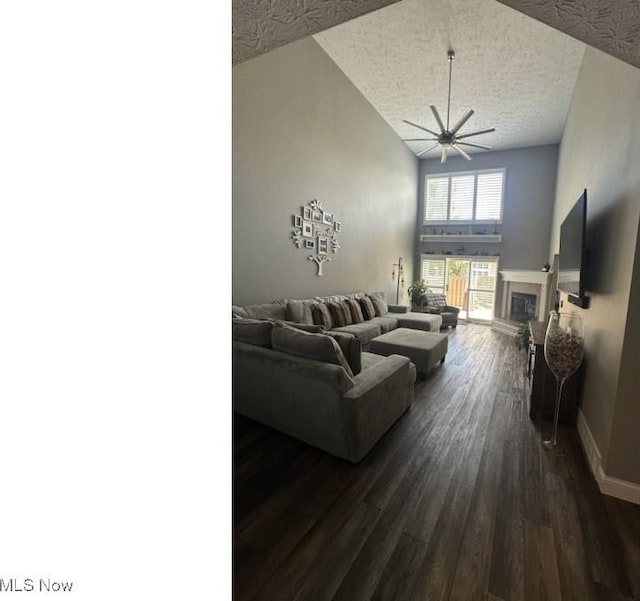 324 Buttermere Ln, Amherst, OH 44001 - living area with a textured ceiling, dark wood-style floors, a tiled fireplace, ceiling fan, and high vaulted ceiling