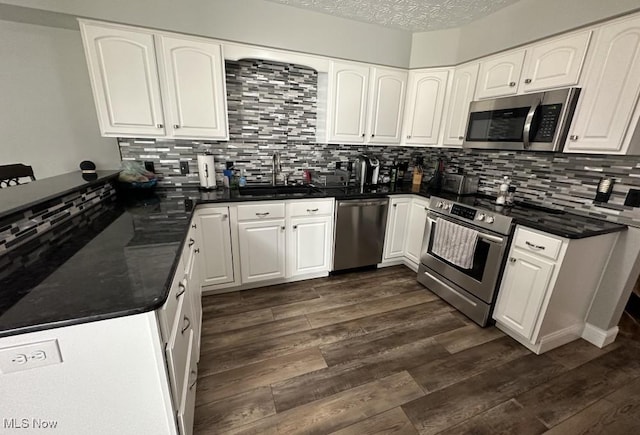 324 Buttermere Ln, Amherst, OH 44001 - kitchen with stainless steel appliances, decorative backsplash, white cabinetry, dark wood-type flooring, and a peninsula