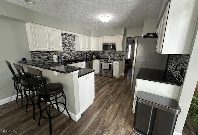 324 Buttermere Ln, Amherst, OH 44001 - kitchen with stainless steel appliances, a peninsula, white cabinets, tasteful backsplash, and a textured ceiling