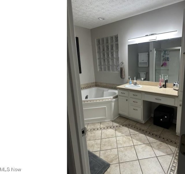 324 Buttermere Ln, Amherst, OH 44001 - bathroom with a garden tub, tile patterned flooring, vanity, and a textured ceiling