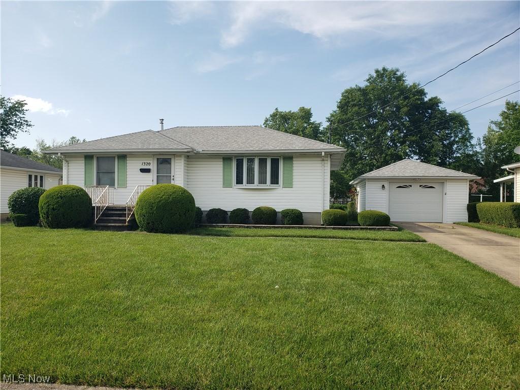 1320 W 40th St, Lorain, OH 44053 - view of front of house with concrete driveway, an outdoor structure, a detached garage, and a front yard