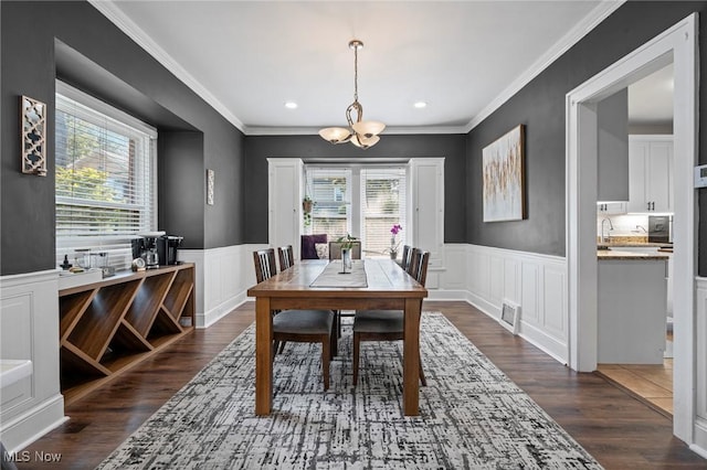 1646 Wyandotte Ave, Lakewood, OH 44107 - dining room featuring healthy amount of natural light, a chandelier, dark wood-type flooring, wainscoting, and crown molding