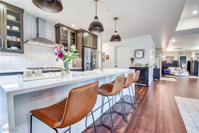 2044 Random Rd Unit 303, Cleveland, OH 44106 - kitchen with wall chimney range hood, decorative backsplash, dark wood finished floors, appliances with stainless steel finishes, and a breakfast bar area