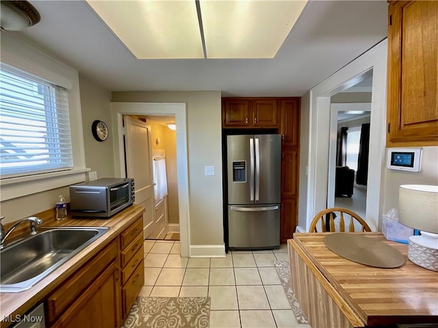 904 Chalker St, Akron, OH 44310 - kitchen featuring stainless steel appliances, light tile patterned floors, healthy amount of natural light, and brown cabinets