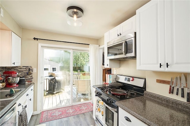 236 Johnson Ave, Cuyahoga Falls, OH 44221 - kitchen featuring stainless steel appliances, dark countertops, light wood-type flooring, white cabinetry, and tasteful backsplash