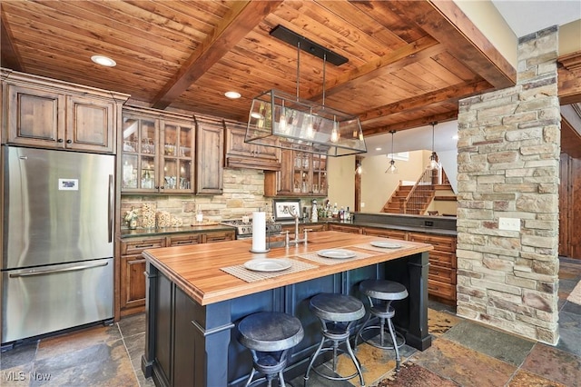 3116 Aviemore Way, Richfield, OH 44286 - kitchen with appliances with stainless steel finishes, wooden counters, a wooden ceiling with exposed beams, stone tile floors, and decorative backsplash