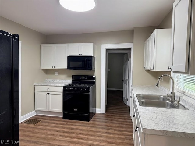 307 Lucas St, Barberton, OH 44203 - kitchen featuring black appliances, dark wood-style flooring, white cabinets, and light countertops