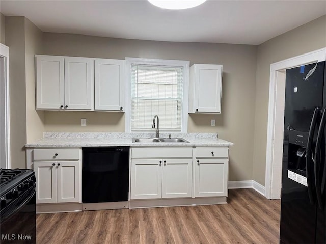307 Lucas St, Barberton, OH 44203 - kitchen with black appliances, light wood finished floors, white cabinets, and light stone counters
