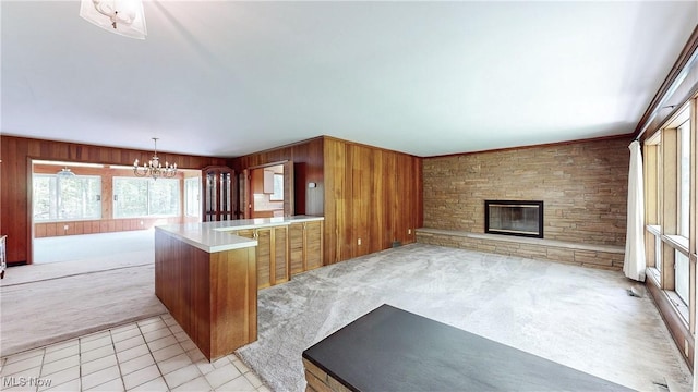7780 Clarion Dr, Chagrin Falls, OH 44022 - unfurnished living room with a chandelier, wooden walls, a fireplace, light carpet, and light tile patterned flooring