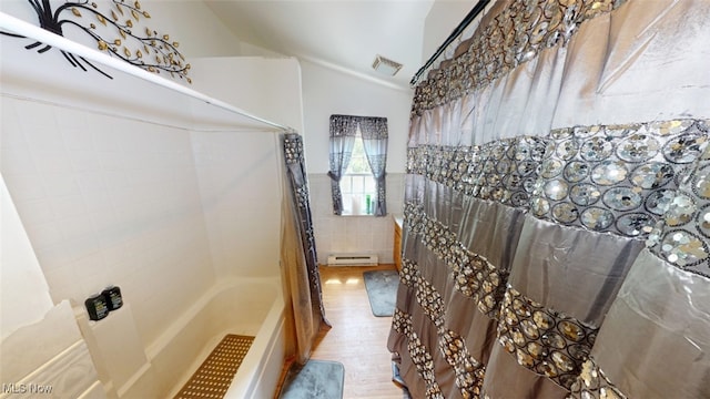 217 Meadowbrook Ave, Boardman, OH 44512 - bathroom with a baseboard heating unit, tile walls, wood finished floors, lofted ceiling, and shower / bath combo with shower curtain