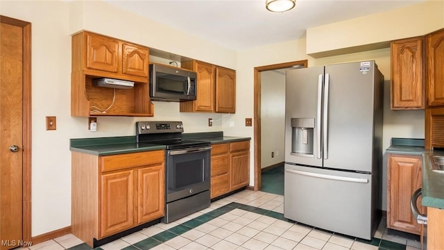 9910 Matchett Rd, Norwich, OH 43767 - kitchen featuring stainless steel appliances, dark countertops, light tile patterned floors, and brown cabinets
