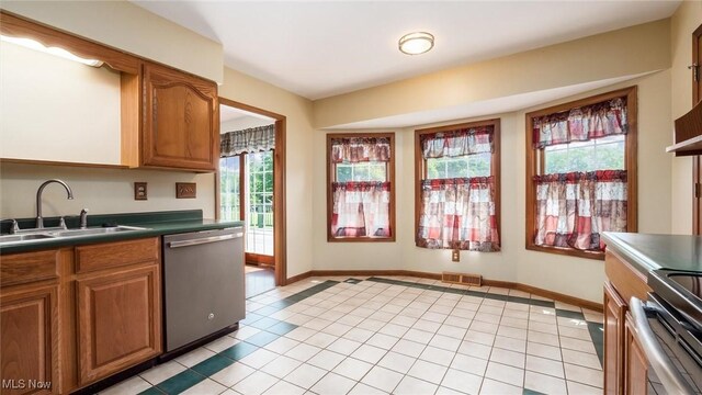 9910 Matchett Rd, Norwich, OH 43767 - kitchen with stainless steel dishwasher, light tile patterned floors, and brown cabinetry
