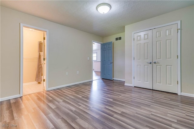 1104 4th St, Belpre, OH 45714 - unfurnished bedroom featuring wood finished floors, a closet, a textured ceiling, and ensuite bath