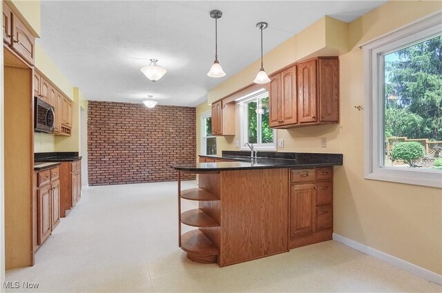 240 S Park Dr, Aurora, OH 44202 - kitchen with stainless steel microwave, brick wall, a peninsula, dark countertops, and healthy amount of natural light