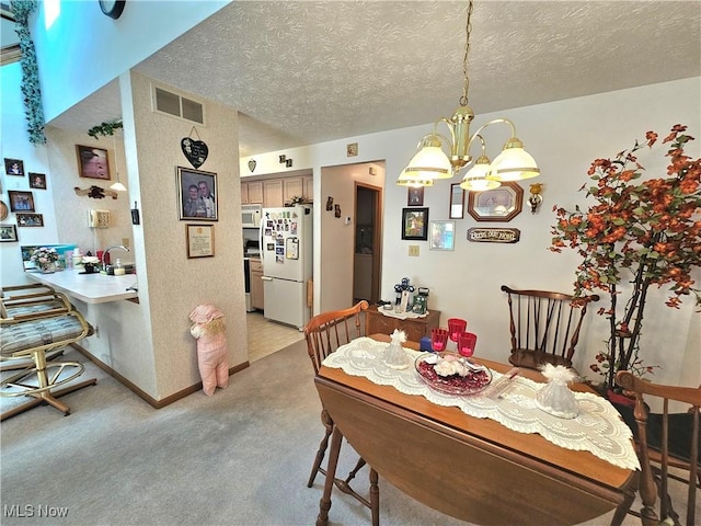 3308 Trappers Trl Unit A, Cortland, OH 44410 - dining space featuring a chandelier, a textured ceiling, and light carpet