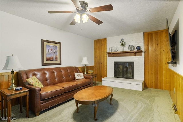 4190 Springdale Rd, Stow, OH 44224 - carpeted living area featuring wood walls, a wainscoted wall, ceiling fan, a fireplace, and a textured ceiling