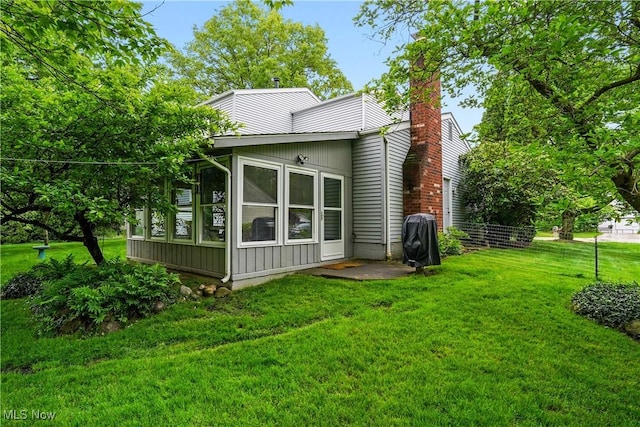 4190 Springdale Rd, Stow, OH 44224 - back of house featuring a sunroom, a lawn, a chimney, and board and batten siding