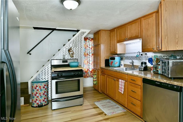 252 E Main St, Newton Falls, OH 44444 - kitchen with stainless steel appliances, light wood-style flooring, brown cabinets, and a textured ceiling
