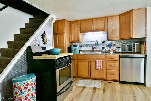252 E Main St, Newton Falls, OH 44444 - kitchen with stainless steel appliances, light wood finished floors, brown cabinets, and backsplash