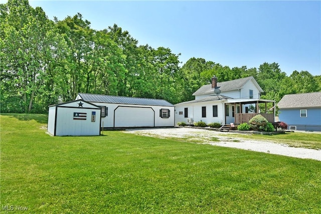 252 E Main St, Newton Falls, OH 44444 - view of front of property with an outdoor structure, a front lawn, a detached garage, and a chimney