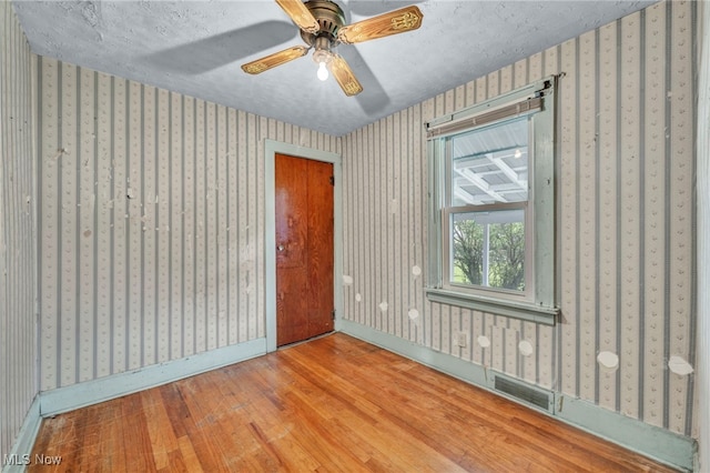 654 Van Everett Ave, Akron, OH 44306 - unfurnished room with wood finished floors, wallpapered walls, ceiling fan, and a textured ceiling