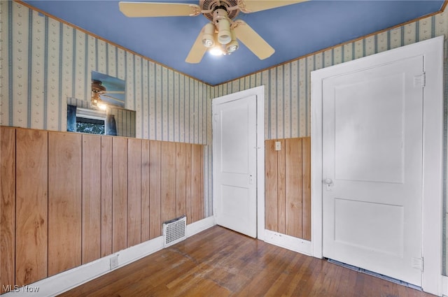 654 Van Everett Ave, Akron, OH 44306 - unfurnished bedroom with wallpapered walls, wood finished floors, ceiling fan, and wooden walls