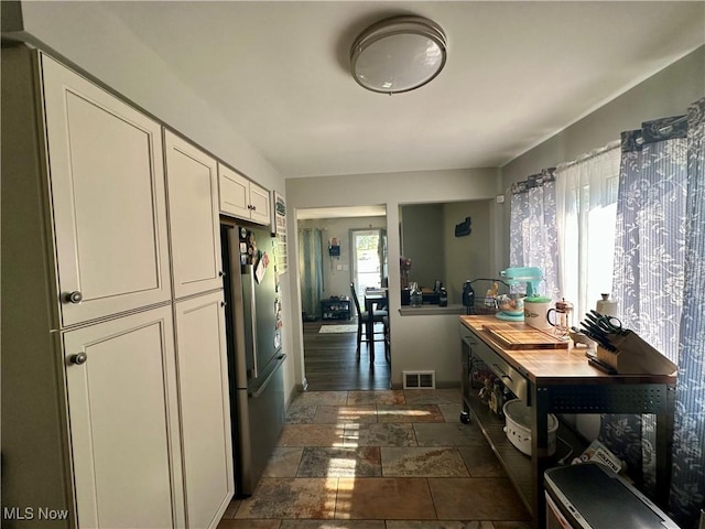 556 Moherman Ave, Youngstown, OH 44509 - kitchen featuring freestanding refrigerator, stone tile floors, and white cabinetry