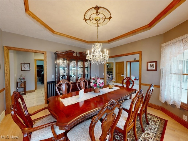 35005 Lisle Ct, Willoughby, OH 44094 - dining room featuring a raised ceiling, a chandelier, healthy amount of natural light, light wood-type flooring, and crown molding