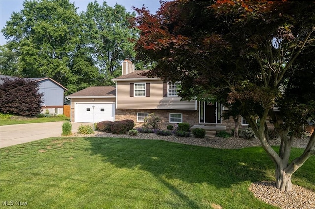 3247 Brooklawn Dr, Norton, OH 44203 - split level home featuring concrete driveway, stone siding, a chimney, a front yard, and a garage