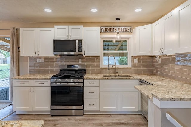2880 Hetzel Dr, Parma, OH 44134 - kitchen featuring appliances with stainless steel finishes, white cabinets, light wood finished floors, light stone counters, and decorative backsplash