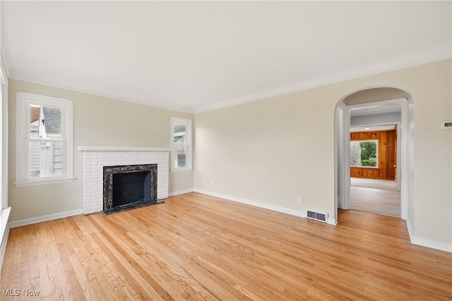 10212 Grace Ave, Garfield Heights, OH 44125 - unfurnished living room featuring light wood finished floors, arched walkways, a brick fireplace, and ornamental molding