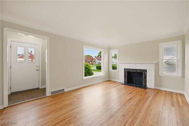 10212 Grace Ave, Garfield Heights, OH 44125 - unfurnished living room featuring light wood-type flooring, healthy amount of natural light, and a fireplace