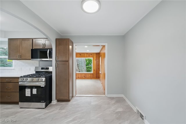 10212 Grace Ave, Garfield Heights, OH 44125 - kitchen featuring appliances with stainless steel finishes, arched walkways, backsplash, light countertops, and wooden walls