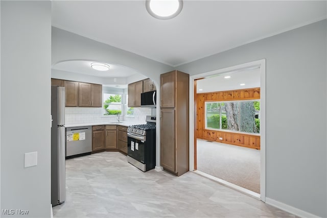 10212 Grace Ave, Garfield Heights, OH 44125 - kitchen with appliances with stainless steel finishes, arched walkways, plenty of natural light, backsplash, and ornamental molding