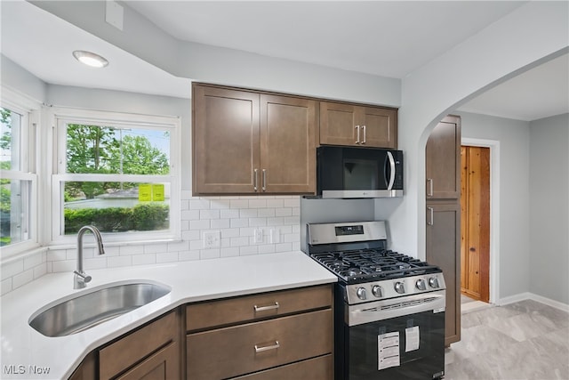 10212 Grace Ave, Garfield Heights, OH 44125 - kitchen with stainless steel gas stove, black microwave, light countertops, arched walkways, and decorative backsplash