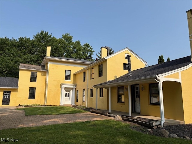989 Orchard Hill Cir, Massillon, OH 44646 - rear view of property featuring a yard, a porch, stucco siding, and a chimney