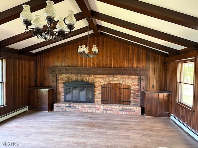989 Orchard Hill Cir, Massillon, OH 44646 - unfurnished living room featuring a chandelier, a baseboard heating unit, wood walls, and wood finished floors