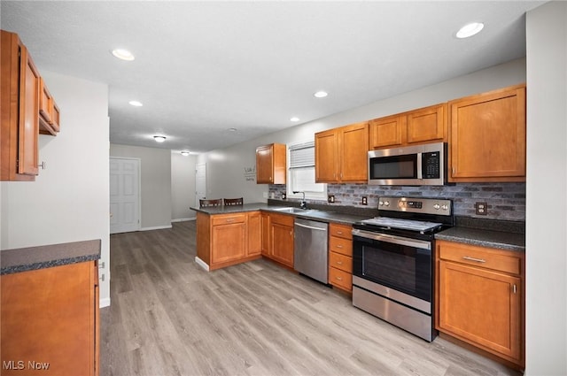 3031 Logan Ln Unit 1, Rock Creek, OH 44084 - kitchen featuring stainless steel appliances, a peninsula, dark countertops, light wood-style flooring, and backsplash