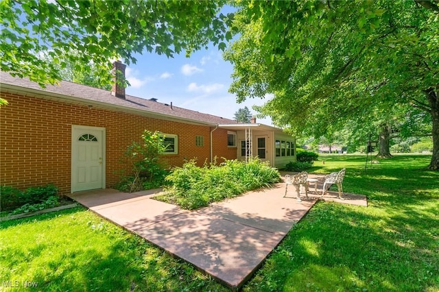 3612 Ridge Rd, Cortland, OH 44410 - rear view of property featuring brick siding, a yard, a patio area, and a chimney