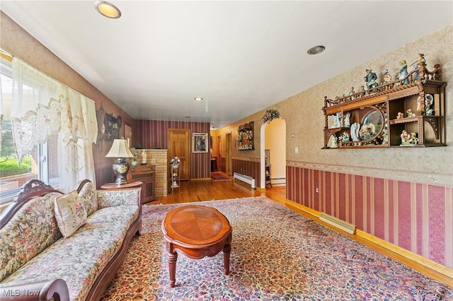 3612 Ridge Rd, Cortland, OH 44410 - living area featuring wallpapered walls, wood finished floors, wainscoting, arched walkways, and a baseboard radiator