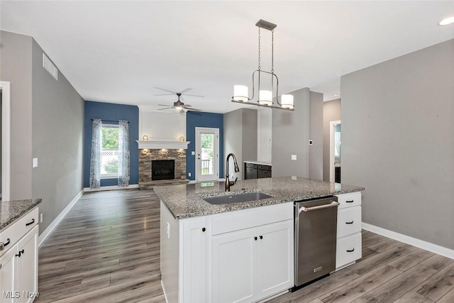 686 Outrigger Cv, Painesville, OH 44077 - kitchen with a ceiling fan, stainless steel dishwasher, a stone fireplace, wood finished floors, and open floor plan