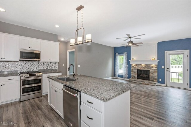 686 Outrigger Cv, Painesville, OH 44077 - kitchen featuring stainless steel appliances, ceiling fan, dark wood finished floors, a fireplace, and backsplash