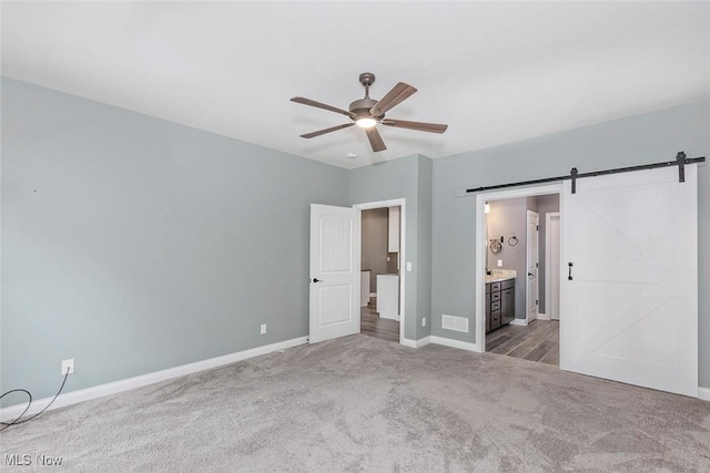 686 Outrigger Cv, Painesville, OH 44077 - unfurnished bedroom featuring a barn door, carpet flooring, ensuite bath, and ceiling fan