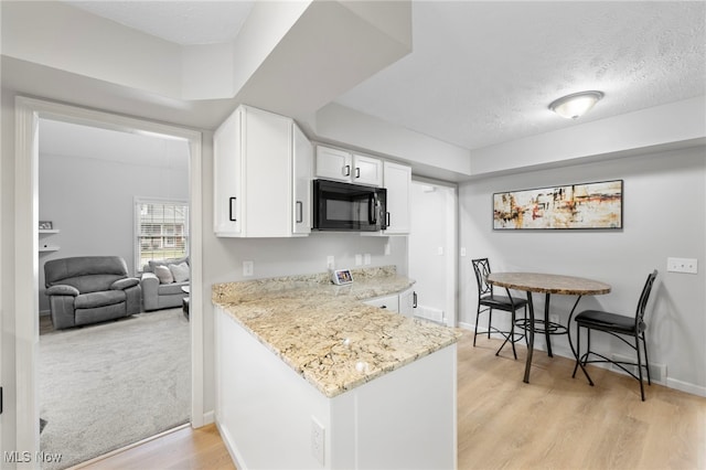 662 2nd St Unit 2, Fairport Harbor, OH 44077 - kitchen with black microwave, white cabinetry, light wood-style floors, light stone counters, and a textured ceiling
