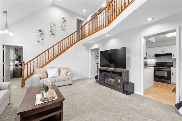 662 2nd St Unit 2, Fairport Harbor, OH 44077 - living room with light colored carpet, stairs, high vaulted ceiling, and recessed lighting