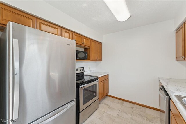 3917 Oxford Dr, Lorain, OH 44053 - kitchen featuring appliances with stainless steel finishes, brown cabinetry, and light stone counters