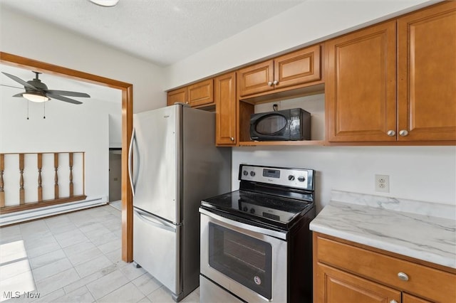3917 Oxford Dr, Lorain, OH 44053 - kitchen featuring stainless steel appliances, a baseboard heating unit, brown cabinetry, ceiling fan, and a textured ceiling